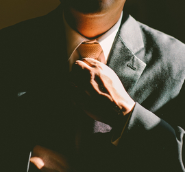 A man in a business suit adjusting his tie